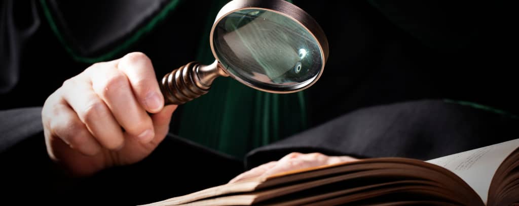 Photo of investigator with magnifying glass reading a book.