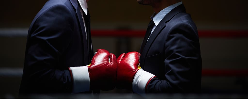 Photo of two people in business suits and boxing gloves