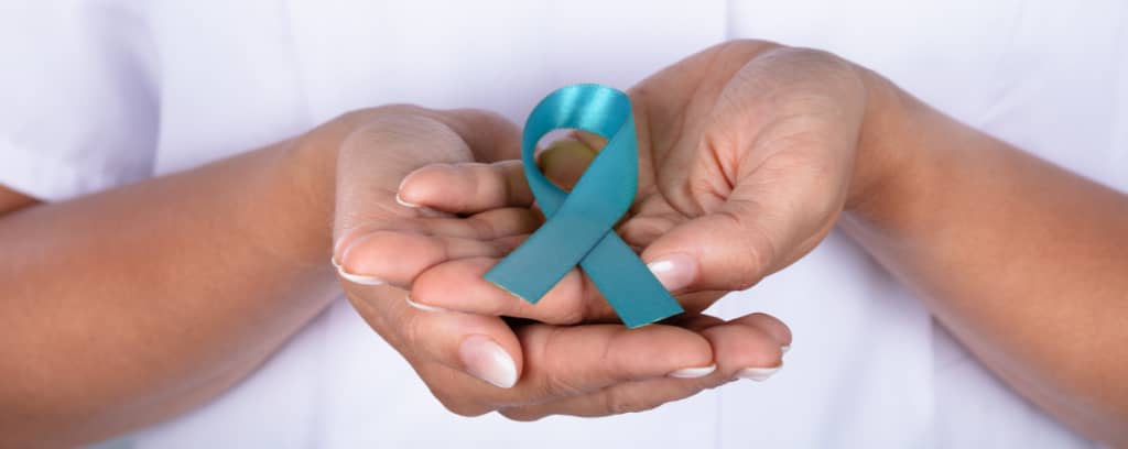 Photo of two hands, one cupping the other, which holds the teal Sexual Assault Awareness Month ribbon.